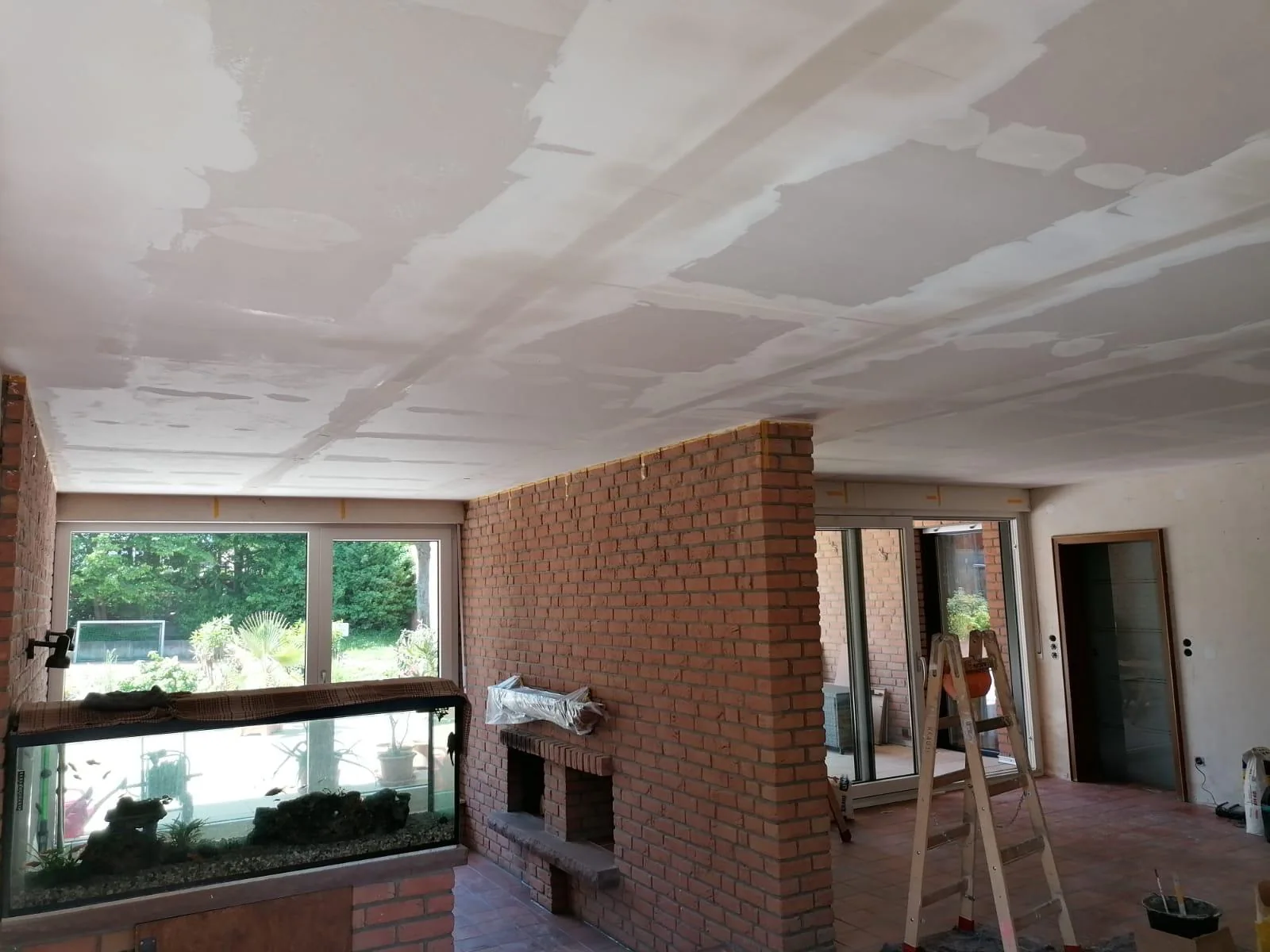 Wohnraum mit gemauertem Kamin und sichtbaren Spachtelstellen an der Decke